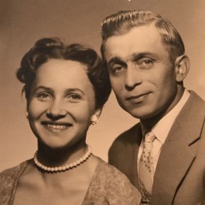 1950-luvun kuvassa nuori nainen helmikorvakoruissaan ja mies vaalea juhlapuku päällään.