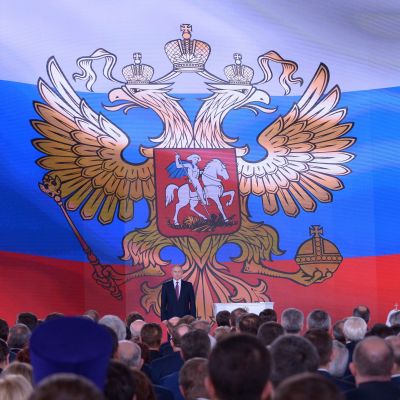Vladimir Putin framför en enorm rysk flagga, då han höll sitt årliga linjetal den 1 mars 2018.