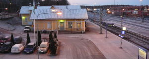 Det gagnar inte tågtrafiken på kustbanan att planera nya bostadsområden utanför centrum, säger de statliga myndigheterna. En gammal gul järnvägsstation, järnvägsspår, parkerade bilar med isiga vindrutor. Skymning.