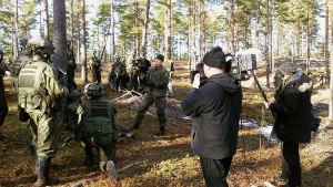 Yles team Marco Hyvärinen och Tomi Dahlman dokumenterar milpastorn "som sparkar kottar och juttar med killarna". inspelningsteam bland beväringar i skog