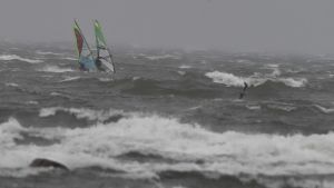 Det är full storm på havet. Den här bilden är tagen på Drumsö i Helsingfors. Vindsurfare åker bland höga vågor.