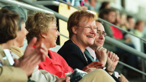 Presidentti Tarja Halonen Katkolla tulevaisuus -konsertin katsomossa vuonna 2002. Ihmisiä Olympiastadionin katsomossa