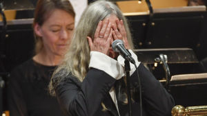 Patti Smith kom av sig.. Patti Smith med händerna över sitt eget ansikte under Nobelfesten i Stockholm.