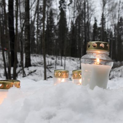 Flera ljus har placerats i snön vi Karabacka där en död 13-åring försvann. 