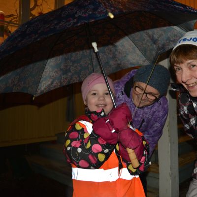 Eskarilainen Lilja Hietikko on ottanut kylämummat Marjatta Tammelan ja Anna-Maija Myllärin yhteisen sateenvarjon alle.