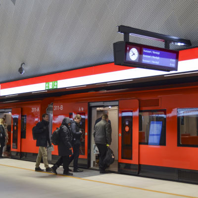 passagerare går in i ett tåg på mattby metrostation på måndag morgon