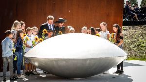 I centrum av monumentskogen finns ett öga av stål som blickar upp mot himlen. På bilden samlas Nederländernas kungapar och lokala barn för att lägga blommor vid ögat. Det nederländska kungaparet och lokala barn samlas för att avslöja minnesmonumentet för offren i MH17-flygkraschen.