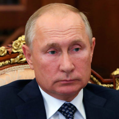 En porträttbild av Vladimir Putin sittandes i en vacker stol.