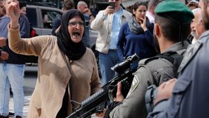 Israel varnar för att demonstrationerna inte blir enbart fredliga. Arg palestinsk kvinna hötter med näven åt beväpnad israelisk soldat.