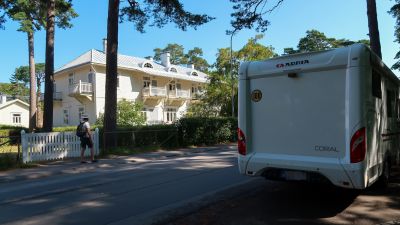 Bild av husbil som är parkerad längs med vägen. På andra sidan vägen står ett hus.
