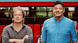 Både Kjell Westö och Kaj Korkea-aho spelar gitarr. Kjell Westö med armarna i kors med småbutter min bredvid en glad Kqaj Korkea-aho i London. Röd buss i bakgrunden.