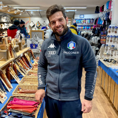 Harmaaseen urheilupusakkaan pukeutunut Italian naisten alppimaajoukkueen fysiikkavalmentaja Davide Mondin seisoo matkamuistomyymälässä Levillä ja katsoo kameraan.