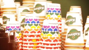 De omtalade muggarna. Vanliga reklamtryckta engångskaffemuggar och muggar med regnbågsmönster i staplar.
