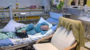 Arkivbild. Cancersjukt ban ligger i patientsäng på sjukhus och använder bärbar dator.