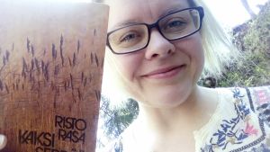 Kirjamielellä-bloggaaja pitää kädessään Risto Rasan kokoelmaa Kaksi seppää
