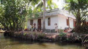 Kerala, Indien Intialainen perhe vilkittaa kotitalonsa edustalla Keralassa.