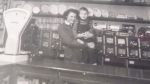Hasse med en av butiksflickorna Svartvitt fotografi taget på 1950-talet i Gröna Boden i Bromarv, en liten matbutik