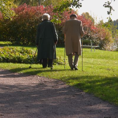 Ett äldre par på promenad en en park.