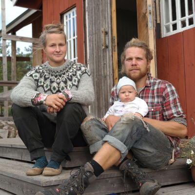 Julia Ajanko och Lennart Söderlund sitter med sin baby på trappan till caféet på Brännskär