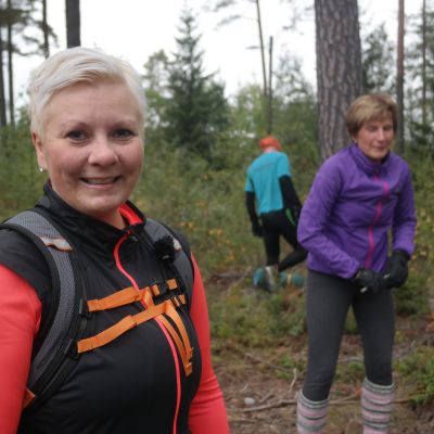 CrossNatureinstruktör Petra Mannström i skogen, två deltagare i bakgrunden