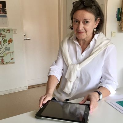 Marianne Öhman sitter vid ett bord med en pekplatta framför sig.