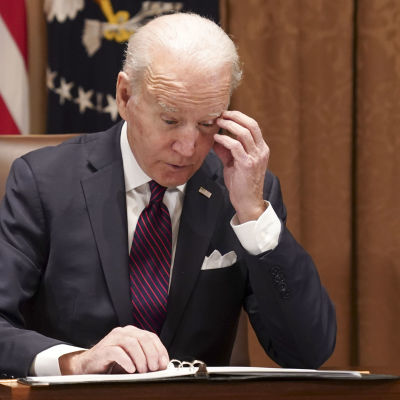 Joe Biden ser bekymrad ut när han läser dokument som ligger på skrivbordet framför honom.