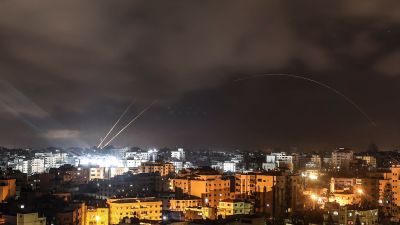 Två ljusspår från raketer syns mot en mörk himmel över en stad