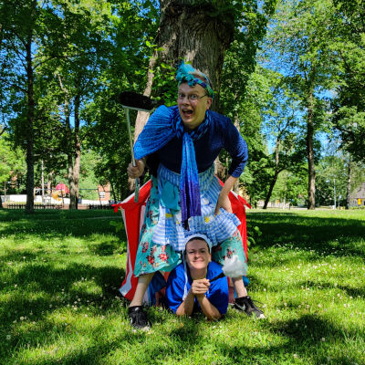 En man och en kvinna utklädda till städerskor i en lummig park.
