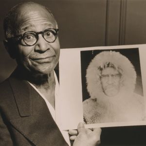 Matthew Henson saavutti pohjoisnavan vuonna 1909 yhdessä Robert Pearyn kanssa. Ihonvärinsä vuoksi hänet sivuutettiin tunnustuksissa. Mustavalkoisessa arkistokuvassa silmälasipäinen tummaihoinen mies puku päällä katsoo kameraan ja pitää kädessään valokuvaa, jossa on turkishuppuiseen takkiin pukeutunut mies