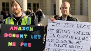 "Amazon låter mig inte gå och kissa" klagar Amazon-anställd på Maxim Matthee-O´Briens plakat. Två män demonstrerar mot Amazon och Jeff Bezos.