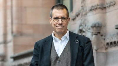 Fredrik Elgh poserar i stilig mörk jacka och grå väst.