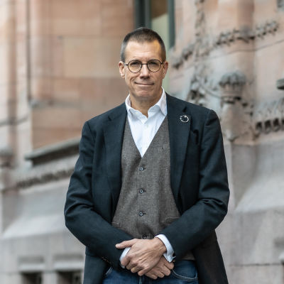 Fredrik Elgh poserar i stilig mörk jacka och grå väst.