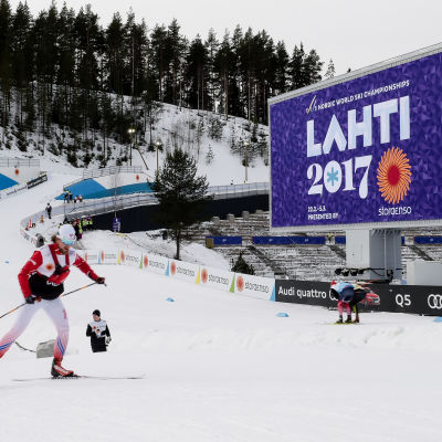 En skidåkare i Lahtis, framför en skylt där det står Lahti 2017.
