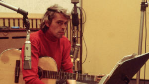 Jacques Brel istuu studiossa kitara kädessä, Kuva dokunenttielokuvasta.