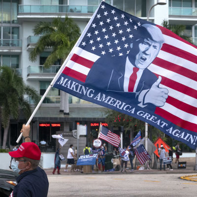 Demonstrant med Trump-flagga utanför tv-huset i Miami där Trump svarade på frågor som en del i kampanjen.
