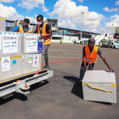 Lådor som innehåller coronavacciner flyttas på en flygplats.