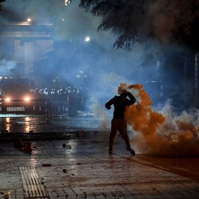 En demonstrant kastar tillbaka polisens tårgasgranater under lördagskvällens sammandrabbningar i Tirana. 