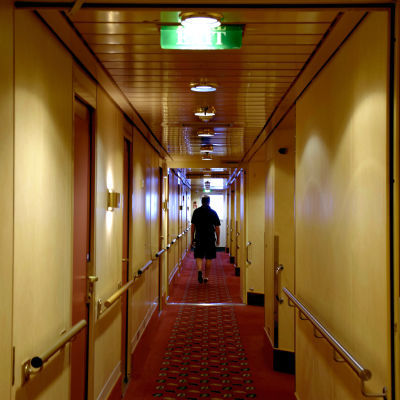 Man går i hyttkorridor på kryssningsfartyg