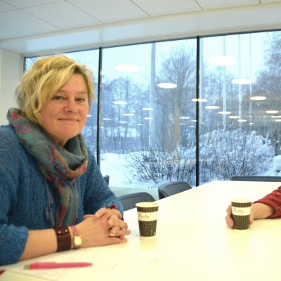 Regina Ekblom och Camilla Gorbatow sitter vid ett bord och dricker kaffe.
