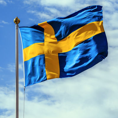 En fladdrande svensk flagga mot blå himmel