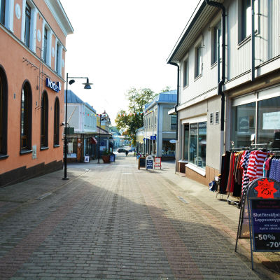 En bild på en folktom gågata. På höger sida står en skylt med texten "slutförsäljning".