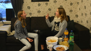 Mariska Nykänen försöker kasta ett popcorn i munnen på Madicken Lund. Ett par gånger lyckas flickorna till och med. Två flickor sitter på en soffa. Den ena har munnen öppen, den andra har ett popcorn i handen som hon försöker kasta i den första flickans mun.