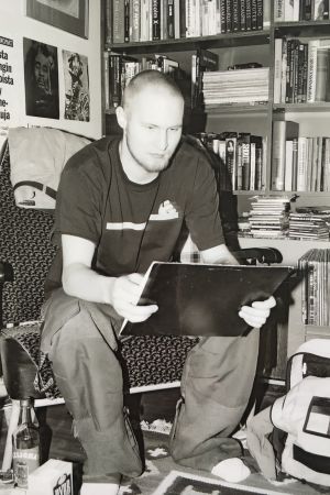 En ung Paleface. Karri har också på senare år fått vara punksångare i bandet HC Andersen som han diggade som ung. Svartvit bild på Palface som ung sittande på stol i arbetsrum med en tavla eller häfte i handen som han studerar.