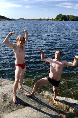 Juontajat Tom Nylund ja Mikko Peltola pullistelevat rantakivillä. 