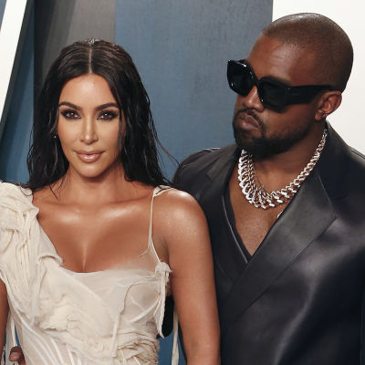 Kim Kardashian vaaleassa iltapuvussa ja Kanye West mustassa nahka-asussa
