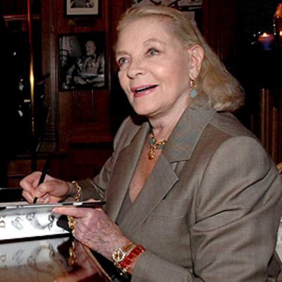 Lauren Bacall kirjoittaa nimikirjoituksiaan omaelämäkertaansa ravintolassa.
