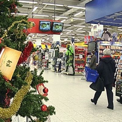 Asiakkaat kävelevät joulukuusen ohi supermarketissa.