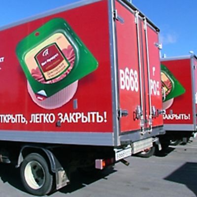 Rivi Atrian jakeluautoja pysäköityinä tehtaan pihalla