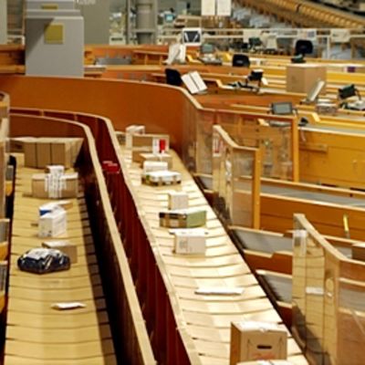 Paketteja kulkee hihnoja pitkin Postin lajittelukeskuksessa.