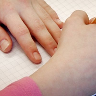 Lapsi kirjoittaa vihkoon alakoulun oppitunnilla.